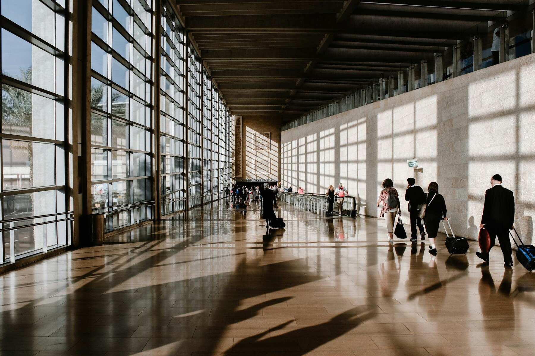 Passageiros atravessando um terminal de aeroporto iluminado pela luz natural