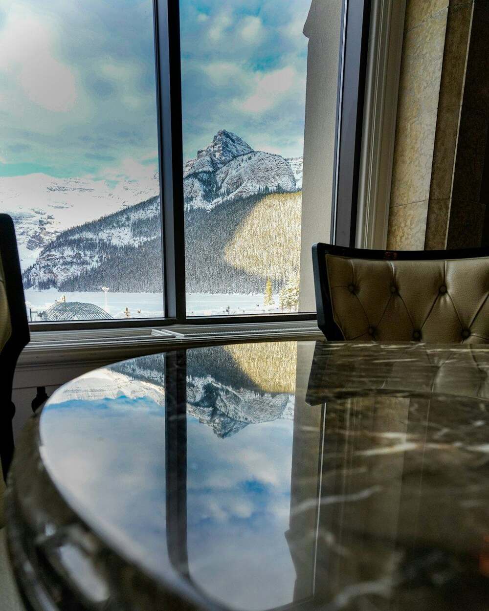Mesa de mármore diante de uma janela com vista para montanhas